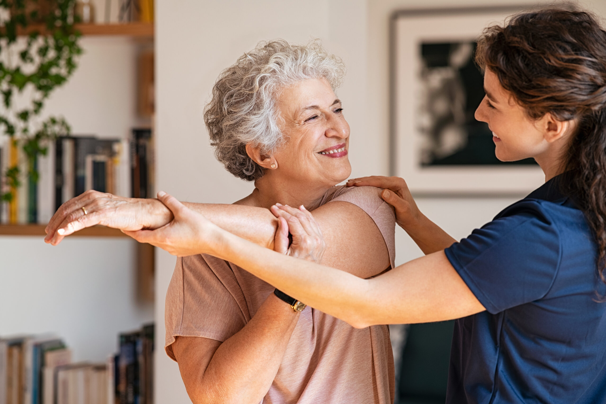 A staff member of a personal care home helps a resident with physical therapy exercises.