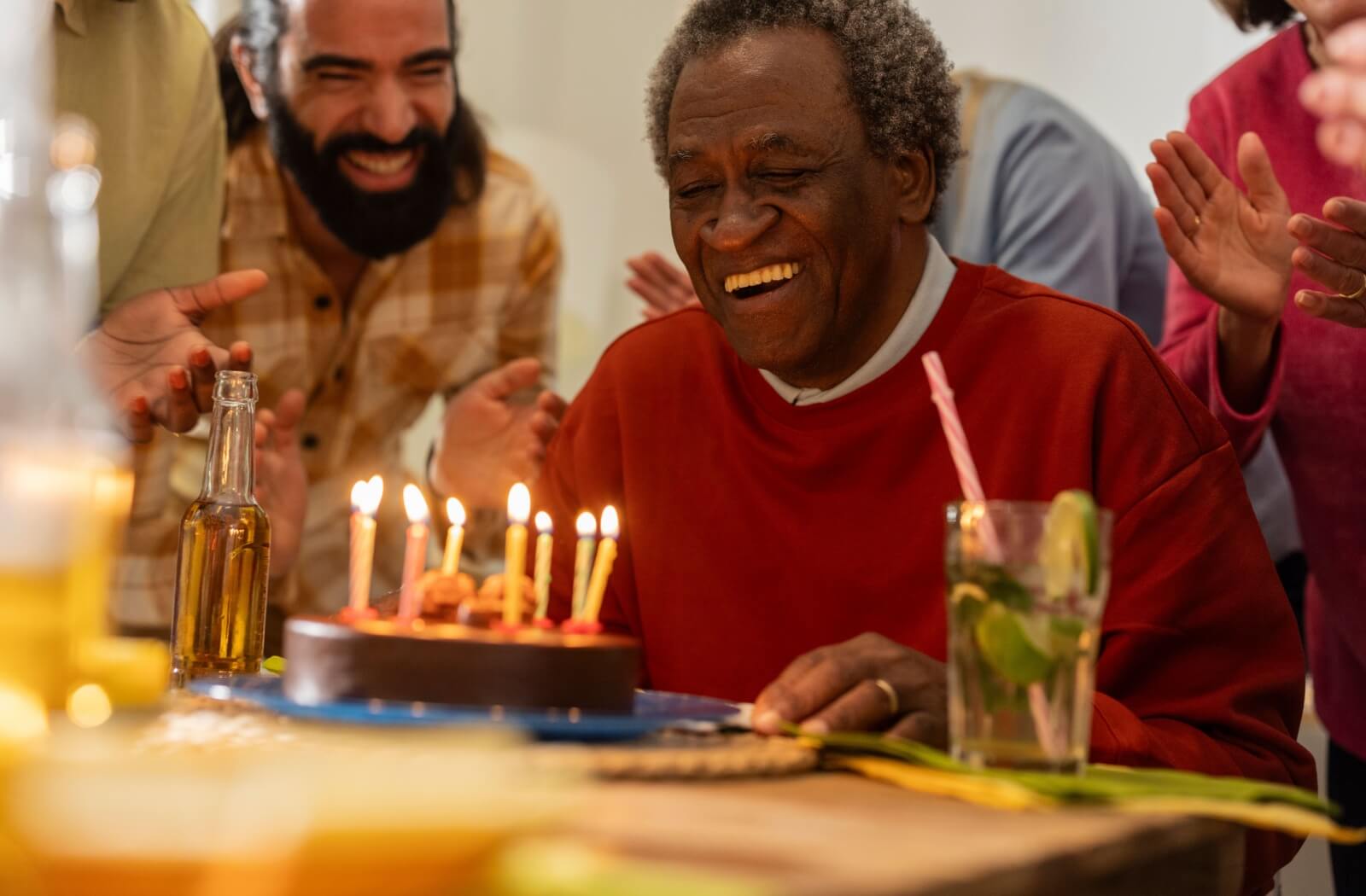 An older adult man laughing during a birthday celebration with a healthy cake.