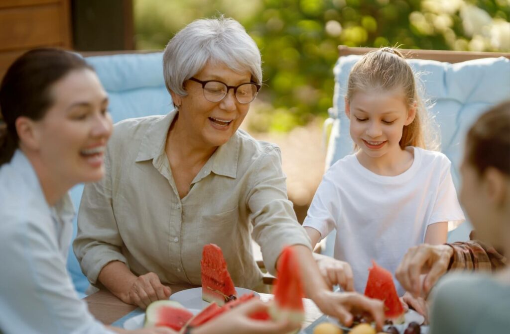 An older adult woman enjoying a healthy meal with her family outdoors.