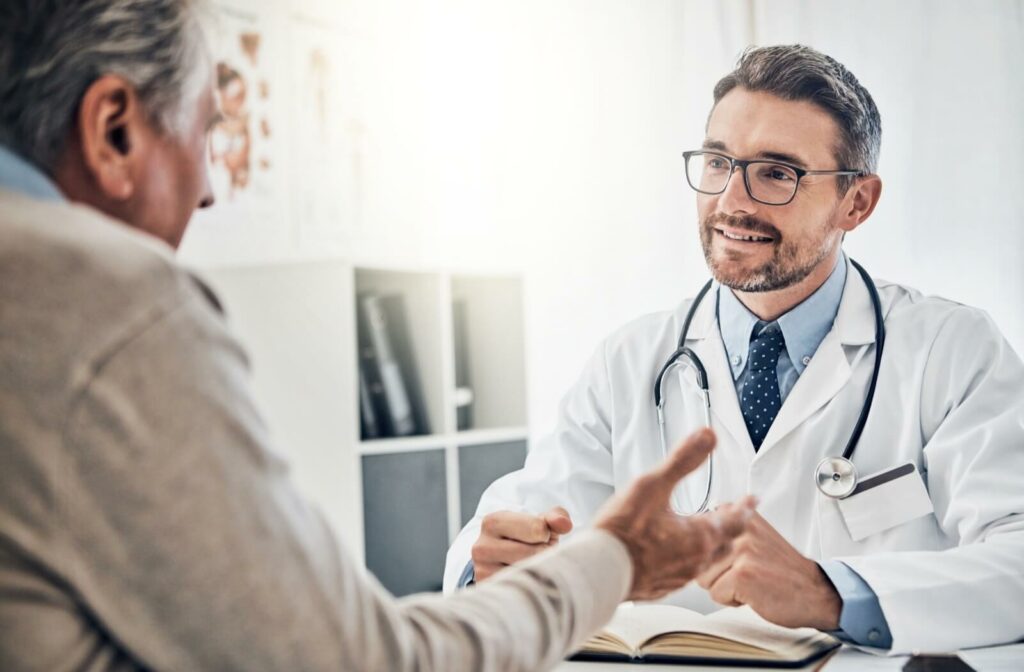 A doctor listening and smiling while discussing how to lower the risk of Alzheimer's disease with an older patient.