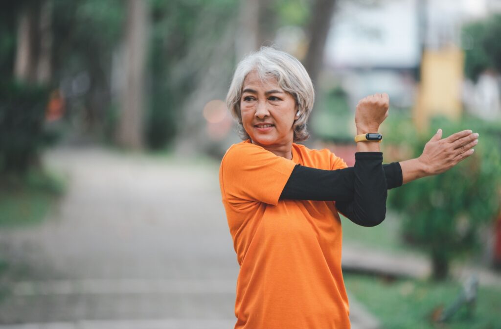 A senior woman warming up with arm stretches before going on a walk to help improve bone density.